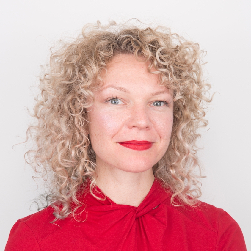 Micheal Hooker headshot wearing blonde hair, red shirt and red lipstick